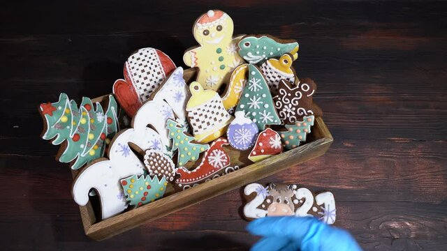 A box of gingerbread and a woman's hand puts Christmas gingerbread to the table.
