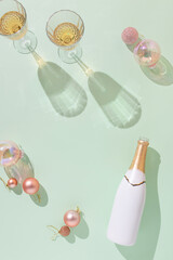 Creative flat lay with white and gold champagne bottle and Christmas decoration against mint green...