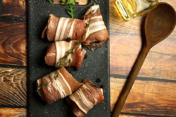Fresh, raw, uncooked pork rolls with wooden spoon on a table. Cooking background.