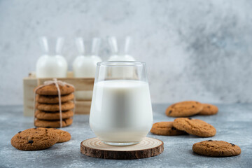 A glass of hot milk with delicious cookies on a gray background