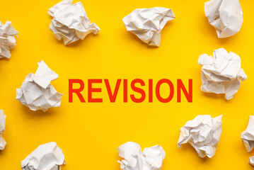 Revision text on yellow background with copy space. Crumpled sheets of paper lie around. Business concept image