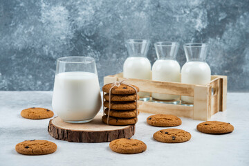 A glass cup of milk with chocolate cookie on a wooden board