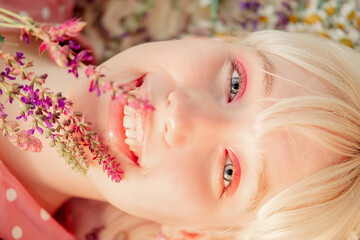 beautiful girl in a pink dress lies on the ground in flowers, a blonde at a picnic in a spring park. woman holding a bouquet of lavender.