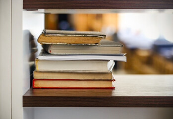 Many books stacked on black shelf with light bokeh