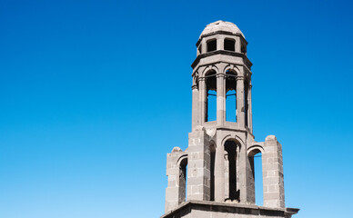 Obraz premium The bell tower of a historic church. Nevsehir, Turkey seen from a distance peeking over the rooftops of old building in the city centre.