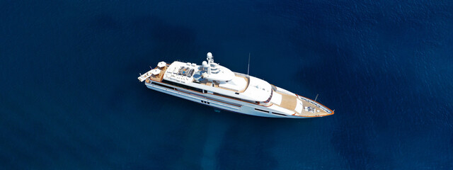 Aerial drone ultra wide photo of luxury yacht with wooden deck anchored in deep blue open ocean sea