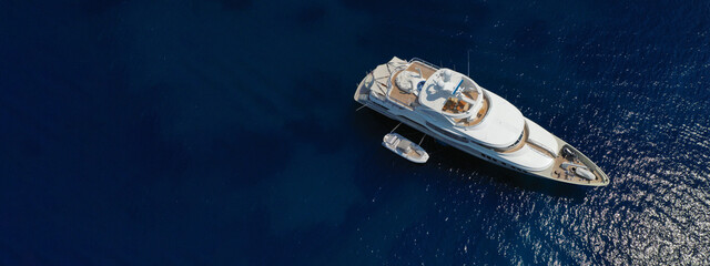 Aerial drone ultra wide photo of luxurious yacht with wooden deck anchored in deep blue...