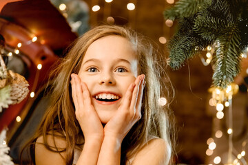 portrait of a beautiful little girl laughing. a child stands near a red car under the snow, New Year's surprise snowfall. concept of happy childhood, making a wish for the new year and birthday.