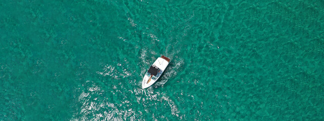 Aerial bird's eye view photo taken by drone of boat cruising in caribbean tropical beach with...