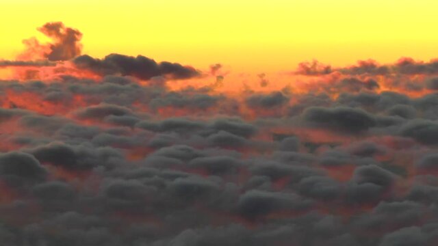 Flying above the clouds; colorful high altitude sunset clouds. Unique, actual, aerial footage. Camera smoothly follows airplane's natural movement in the air for added realism.