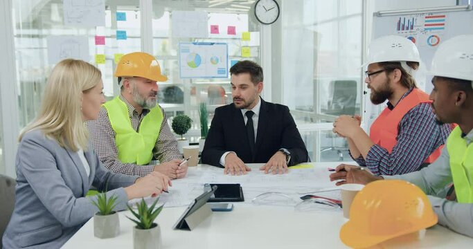 Building industry concept where attractive in good mood professional team of engineers handshaking with positive successful bearded main manager having agreeing all details of joint building project