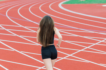 Young, beautiful girl athlete in sportswear is training at the stadium