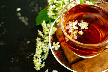 A cup of flower tea with spring cherry blossom on a black background. Copy space