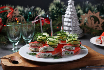 Fototapeta na wymiar Crab stick canapes with cheese and cucumber in a New Year's composition. Delicious festive snack. Horizontal format