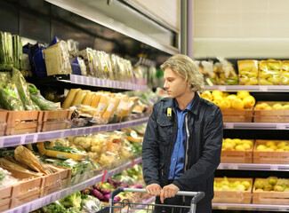 Young man buying vegetables and fruits at the market..