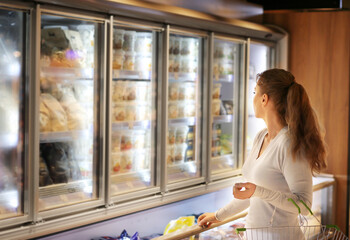 Woman choosing frozen food from a supermarket freezer..