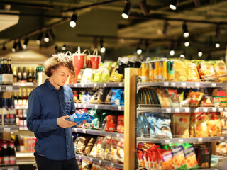 Teenager shopping in supermarket, reading product information