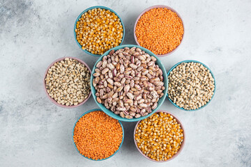Bunch of various uncooked beans, corns and red lentils in bowls