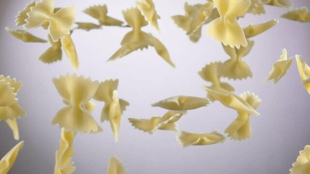 Dry pasta Farfalle is flying up on a white background in slow motion