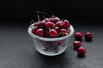 a bowl of fresh and washed Cherries with water drops on dark rustik background. dark photo. Cherry, Berry. glass bowl. 
