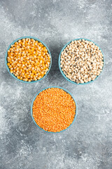 Fototapeta na wymiar Various raw beans, corn kernels and red lentils on marble background