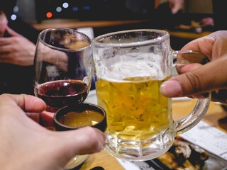 Hands holding a beer, wine and sake and clinking glasses and 