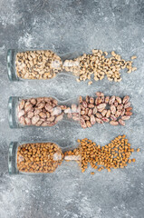 Three glasses of jar with unprepared beans on a gray background