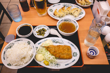 Japanese dinner with fried fish, salad, potatoes, rice, soup, gyozas and soy sauce