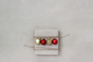 Gift box decorated with red and yellow Christmas balls on craft paper background. Place for text