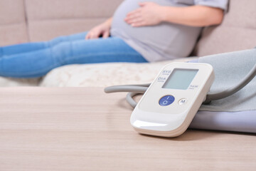 Fototapeta premium blood pressure monitor and pregnant woman on the couch