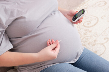 pregnant woman holding a glucometer and a lancet