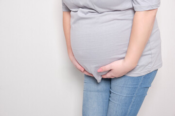 pregnant woman grabbed her belly, light background, color trend