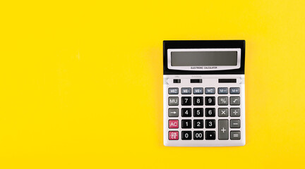 Large silver calculator with black buttons on yellow background with copy space. Conceptual photo of calculation, counting, accounting, computing, profit, loss, tax. Business card. Digital stationery