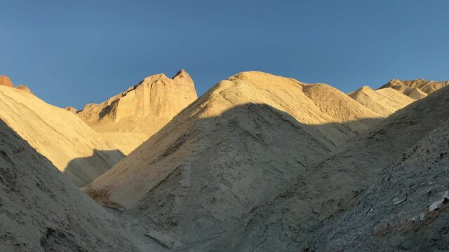 Golden sunset at the rims of the hills at Golden Canyon at Death Valley National Park, CA, USA. Slow pan to the left.