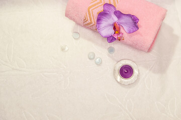 Spa still life - a flowers and towels on a white background. Beige, pink and white tones. The view from the top.