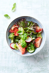 Salad with radish, green olives, tomatoes, cucumber and fresh basil. Bright wooden background. Top view.