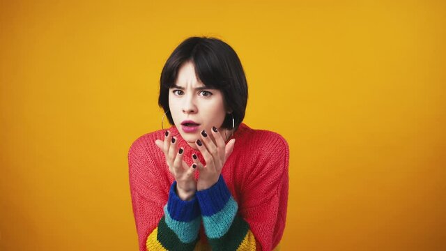 Studio portrait of young shocked woman looking at camera, feeling amazed and stunned, orange background