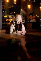 girl on a winter evening sits and holds a phone in her hands