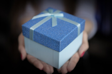 One gift box in woman hands on blurred background