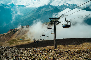 Close up of empty cableway in mountains. Modern ropeway with benches in cloudy weather.