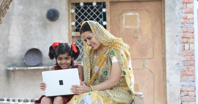 Rural girl with mother using laptop at village
