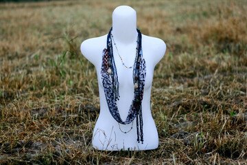 mannequin in the field with many necklace