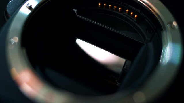 Close-up of the mirror and matrix of a professional camera. Close-up shot of the bayonet connection of a camera lens. Neon light on photo camera