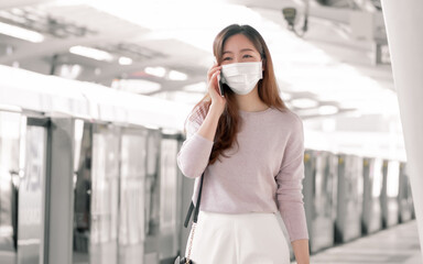Fototapeta premium Woman wearing face mask and talking on mobile phone while standing on railway station