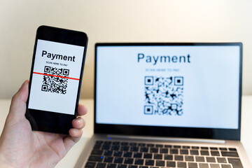 Man's hand uses a mobile phone application to scan QR codes in online stores that accept digital payments without money. Cashless technology concept