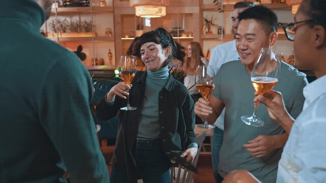 Lets get party! Multi-race happy company young attractive friends gathering in cafeteria and dancing into music while celebrating party holidays and drinking wine together. Friendly atmosphere concept