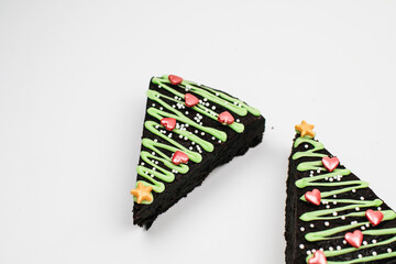 Fresh Homemade Chocolate Brownie  with green icing and festive sprinkles close up. Sweet homemade Christmas or winter holidays pastry food concept. 