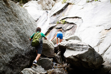 young children climbing boulders on a hike