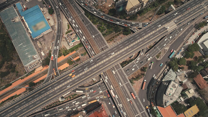 Cross highway top down at Philippines cityscape aerial. Cars, buses, vans, trucks ride at traffic roadway of Manila city. Urban scenery with buildings, skyscrapers, cottages at road