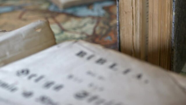Close-up tilt of ancient Swedish bible, focus shift to other old books